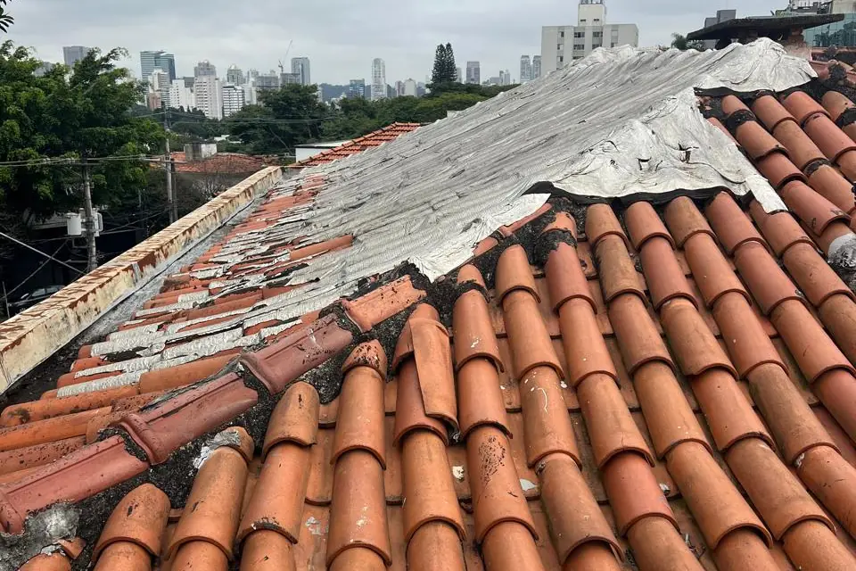 Telhado cerâmico antigo com telhas deslocadas e estrutura exposta, antes da recuperação